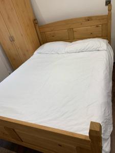 伦敦Private room, renovated with large size white desk In SE9 6PG的一张带木制框架和白色床单的床