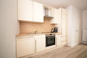 拉本基尔兴-福吕克Schleiblick App 10的厨房配有白色橱柜和水槽