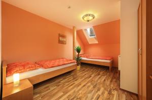 伏尔塔瓦河畔罗日姆贝克乌马丁纳酒店的橙色墙壁和木地板的客房内的两张床