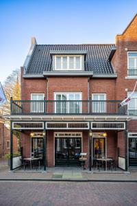 阿斯米尔Hotel Aalsmeer的红砖建筑,设有阳台和桌子