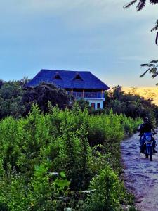 江比阿Sabali Lodge, Zanzibar的骑摩托车的人在房子前面的土路上骑着摩托车