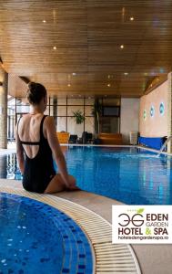 坎普朗莫道尼斯Hotel Eden Garden Spa的坐在游泳池前的女人