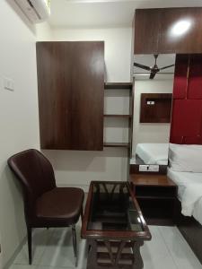 孟买Hotel Royal Grand - Near Mumbai International Airport的一间带椅子、桌子和床的房间