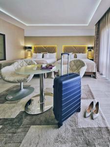坎普朗莫道尼斯Hotel Eden Garden Spa的酒店客房带行李箱和卧室