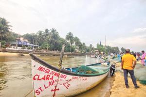 卡兰古特The Baga beach 24in的站在海滩上船旁的人