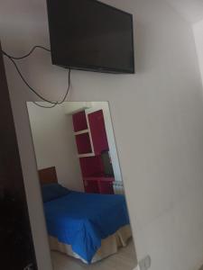 卡特里耶尔hotel el retorno的一间卧室配有一张床,墙上设有一台平面电视