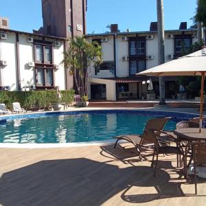 伊瓜苏达曼酒店的一个带椅子和桌子的游泳池以及一把遮阳伞