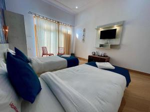 克久拉霍La Curcuma Luxury Homestay的酒店客房设有两张床和一台平面电视。