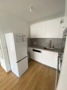 基扬古尔Appartement JO, proche Paris的厨房配有白色橱柜和白色冰箱。