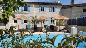 ChaniersLes Cuves - Saintes的一个带稻草遮阳伞的游泳池的度假酒店