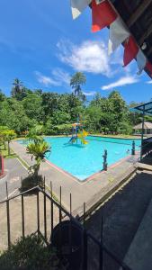 PereanRUMAH KAYU MATARAJA VILLA - TABANAN的公园内一个带游乐场的游泳池