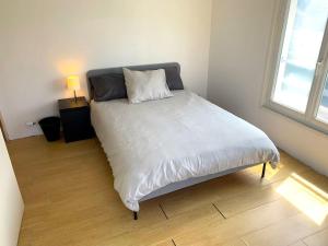 洛里昂Le Marco Yourhosthelper Conciergerie的卧室配有一张带白色床单的大床和窗户。