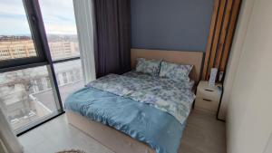 塔什干ЖК Akay city. Новый ремонт的一间卧室配有一张带蓝色棉被的床和窗户。