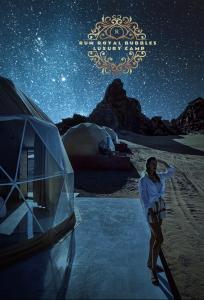 瓦迪拉姆RUM ROYAL BUBBLES lUXURY CAMP的站在星空下的帐篷旁的女人