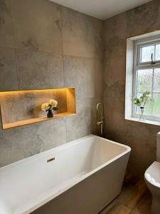 哈罗盖特Chequers Inn的带窗户的浴室内的白色浴缸