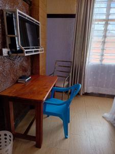 VoiOasis Hotel and Guest House. Voi的一张带蓝色椅子的木桌和一台电视