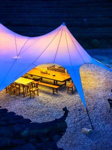 张家界Zhangjiajie National Forest Park Camping的大型帐篷,晚上配有桌子和长凳