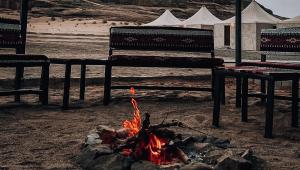 瓦迪拉姆Solana Desert Camp的沙子里的火,有两把长椅和帐篷