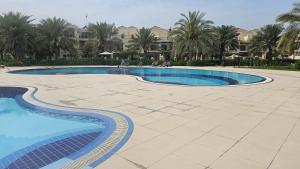 拉斯阿尔卡麦Luxury villa 4 bedroom with pool access的一座棕榈树大型游泳池和一座建筑