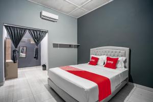 巴东SUPER OYO Gandaria Guest House Near Masjid Raya Sumatera Barat的一间卧室配有一张带红色枕头的大床