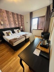 迪沃讷莱班Le Divona的酒店客房设有两张床、一张桌子和一张桌子。