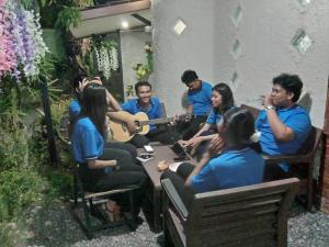 Ban Pak Ba RaMaidok Homestay 2(ไม้ดอกโฮมสเตย์ 2)的一群人坐在一张桌子旁弹吉他