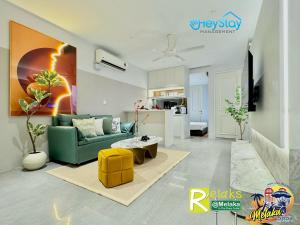 马六甲Imperio Residence By Heystay Management的客厅配有绿色沙发和黄色凳子