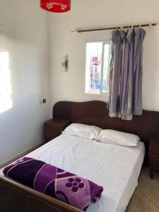 依索安Oceana surf house的一间卧室配有一张床铺,床上铺有紫色毯子