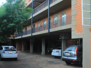 比勒陀利亚Lea's Furnished Apartments - Lofts at Loftus的两辆汽车停在大楼前的停车场