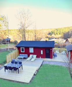 ÅbyRenoverat boende med närhet till Kolmårdens djurpark的红色的建筑,设有野餐桌和甲板