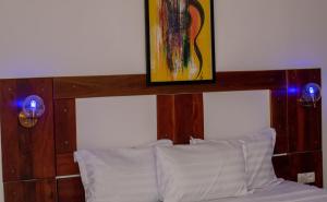 科托努Hotel BKBG Benin的一张带木制床头板的床铺,上面有绘画作品