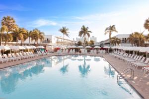 圣徒皮特海滩海滩明信片旅馆的一个带椅子和遮阳伞的大型游泳池