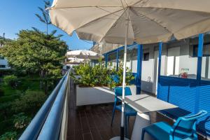丰沙尔马尔露台套房酒店的阳台配有桌子和雨伞。
