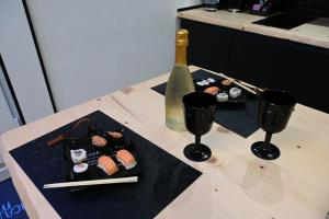 布林迪西DUCA DEGLI ABRUZZI Modern House LUXURY RELAX的一张桌子,上面放有两盘寿司和一瓶清酒