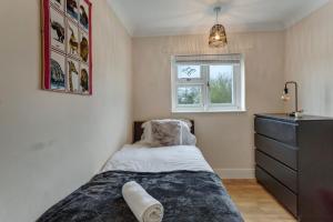 巴塞尔顿Spacious & Centrally Located Home in Basildon With Parking Close to Town Centre的一间卧室配有一张床、一个梳妆台和一扇窗户。