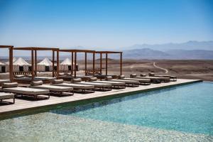 El KariaLes Terrasses d'Agafay的一个带椅子的游泳池的度假村,享有沙漠美景