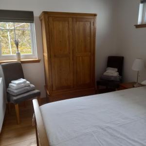 EyreKeistle Cottage的一间卧室配有一张床、两把椅子和一个窗户