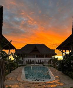 瓦塔穆Nadia&Ale House - Maisha Resort的一座享有日落美景的建筑前的游泳池