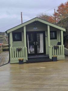 多尼戈尔Sea Breeze cabin的一座带门廊和门的绿色小房子