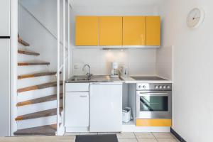 克吕茨Ferienhaus Teichblick的一间设有黄色橱柜和楼梯的小厨房
