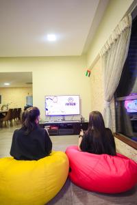 迪拜Lunar Hostel Plus的两个坐在豆袋上看电视的女人