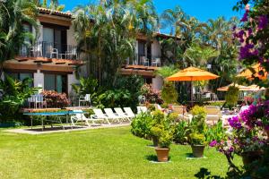 巴亚尔塔港布埃纳文图拉庄园墨西哥魅力酒店 - 全包 的酒店庭院设有椅子和遮阳伞,鲜花盛开