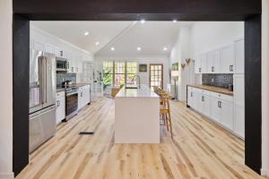 莫尔特里Urban Farmhouse with a Modernism Twist! home的厨房铺有木地板,配有白色橱柜。