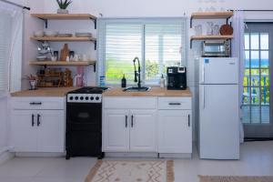 Tulixx Cayman Villa的厨房配有白色橱柜、炉灶和冰箱。