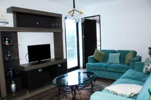 圣萨尔瓦多The Luxury Apartment的客厅配有蓝色的沙发和电视