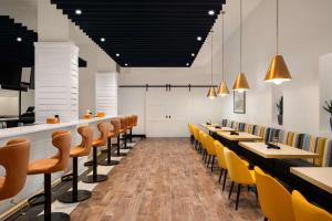 诺福克诺福克机场希尔顿逸林酒店的用餐室配有木桌和黄色椅子