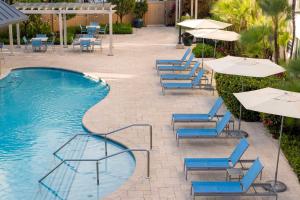 圣胡安圣胡安汉普顿套房酒店的一个带蓝色桌椅和遮阳伞的游泳池