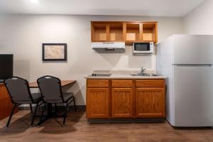 格林维尔WoodSpring Suites Greenville Central I-85的厨房配有白色冰箱、桌子和椅子