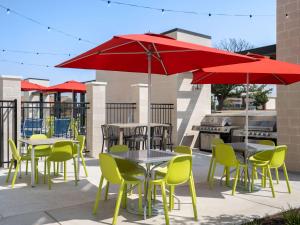 圆石城Home2 Suites By Hilton Round Rock Medical Center的一个带桌椅和红色遮阳伞的庭院