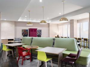 圆石城Home2 Suites By Hilton Round Rock Medical Center的餐厅设有绿色和红色的椅子和桌子